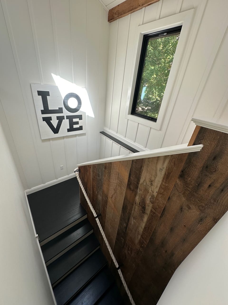 Reclaimed barn wood staricase with unique rope handrail leads downstairs. 