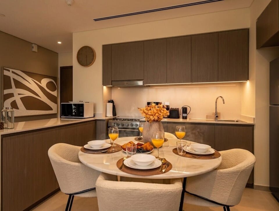 Dining Area Set Table with Croissants Orange Juice Kitchen and Backlit Cabinets