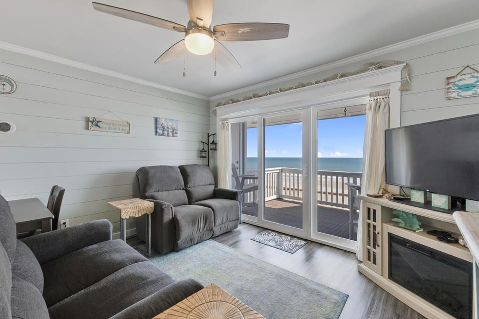 Relax in comfort while enjoying stunning ocean views through your private balcony doors in this coastal living room.