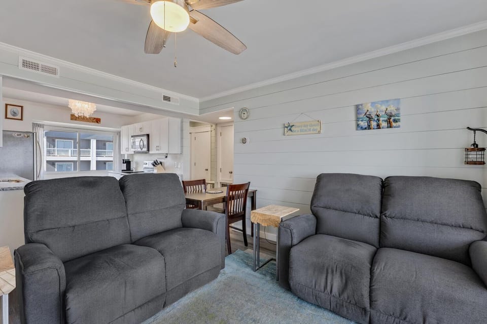 Your beach-themed living space offers comfortable recliners and an open layout connecting to the kitchen for seamless relaxation.