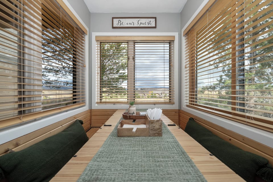 Settle into your peaceful nook with stunning views through warm wooden blinds, where comfortable seating invites relaxation.