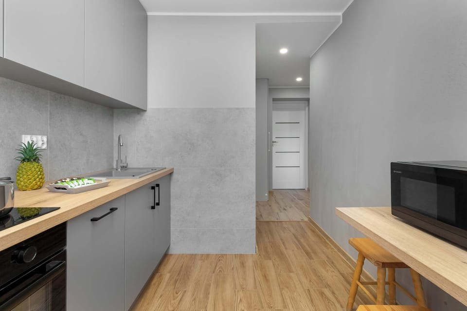 A modern kitchen with gray cabinetry and wooden countertops. The space includes appliances like an oven and microwave.