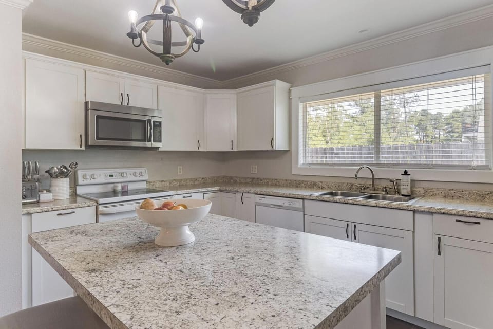 Modern kitchen with granite countertops, stainless steel appliances, and a sunny windowed sink.