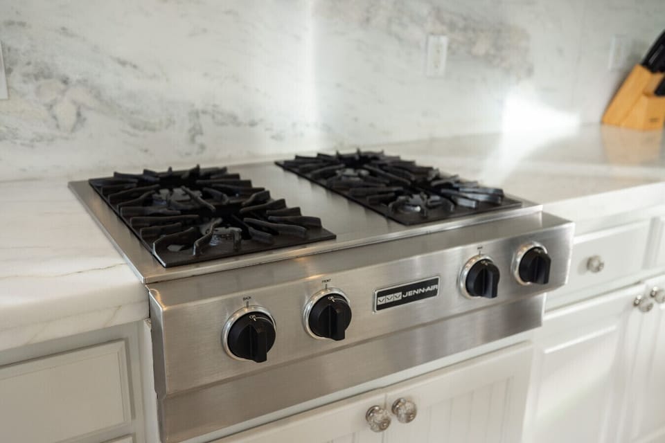 Stainless steel gas cooktop with marble counters and plenty of prep space.