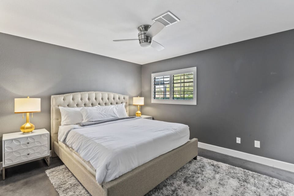 Comfortable bedroom w/ tufted headboard, warm lighting & neutral tones