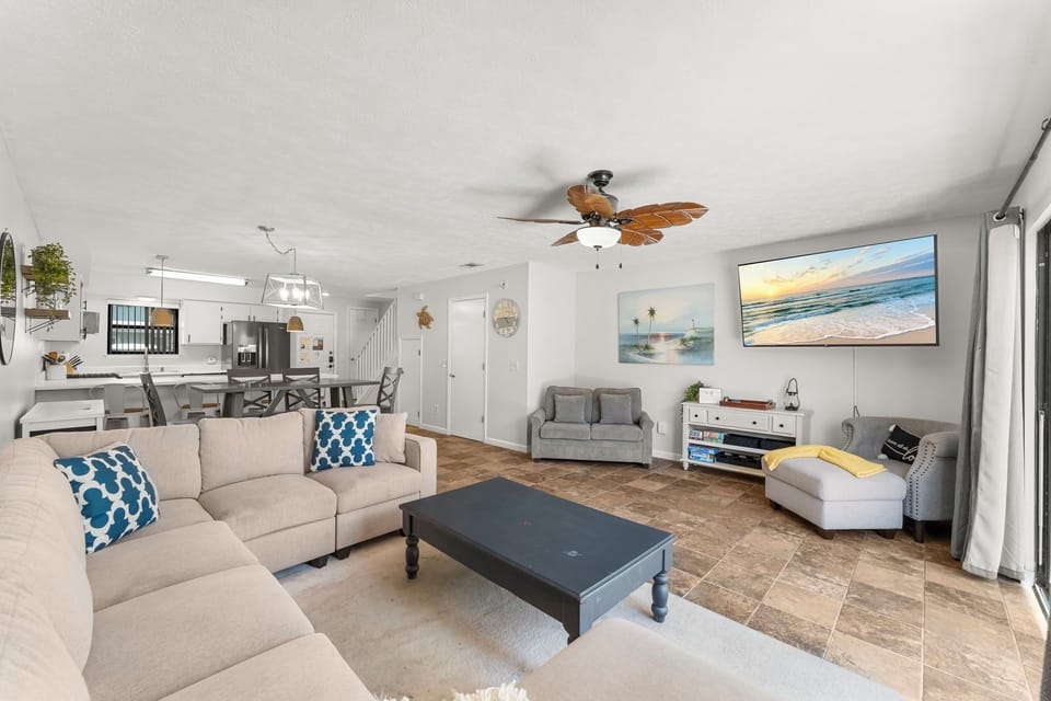 Spacious living room with modern furnishings and a large wall-mounted television.