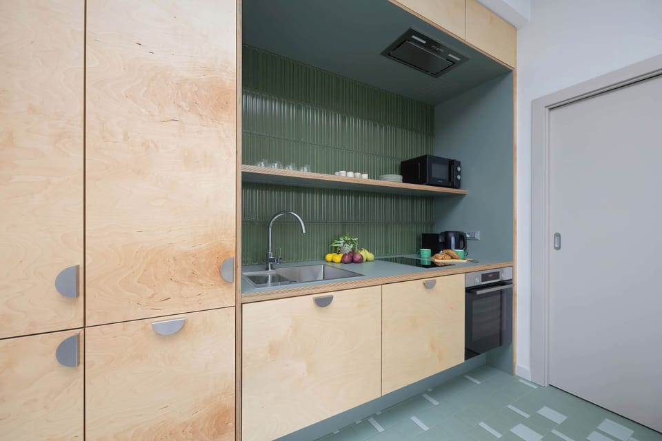 The modern kitchen with wooden fronts and green finishes is fully equipped to prepare any meal with ease.