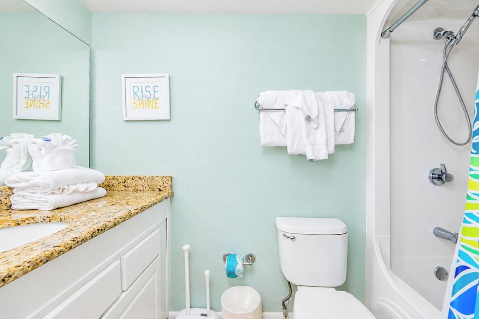 Experience a refreshing guest bathroom with a spacious granite countertop, ample towels, and soft lighting