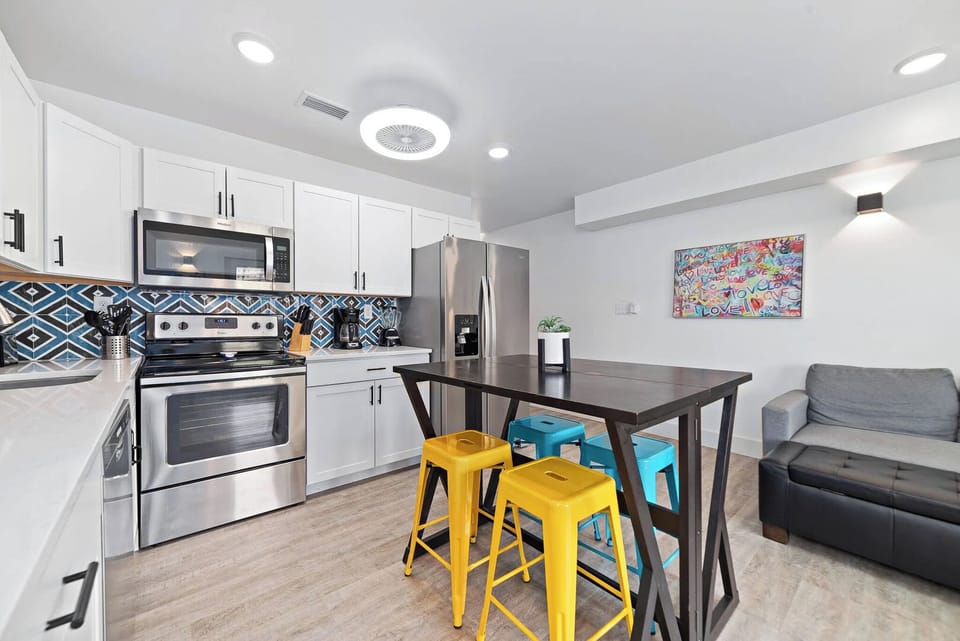 Elegant and fun kitchen featuring stainless appliances, colorful bar stools, and stylish decor for a welcoming atmosphere