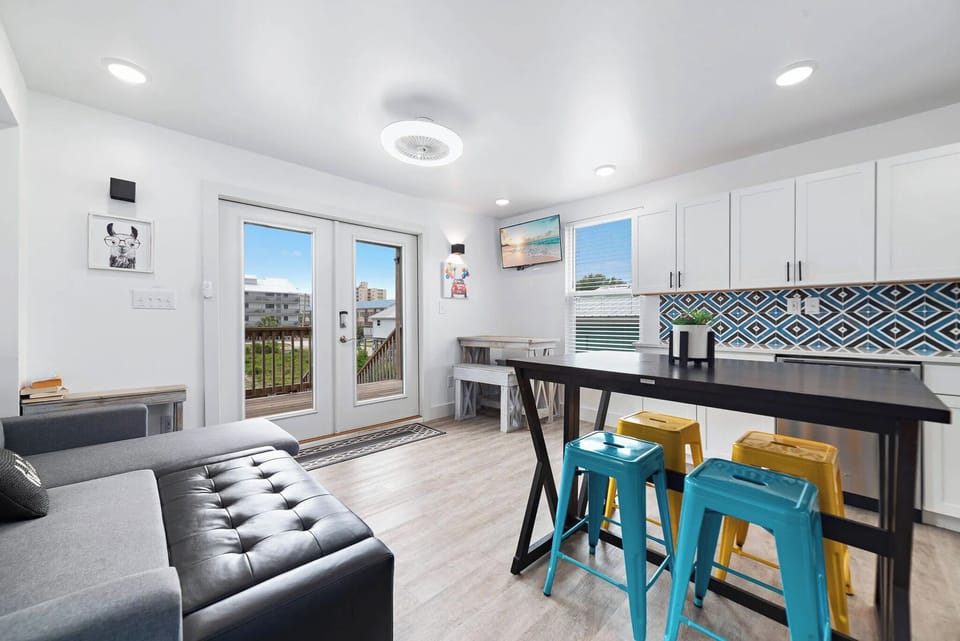 Living space featuring a cozy couch, colorful bar stools, and doors opening to a scenic outdoor view