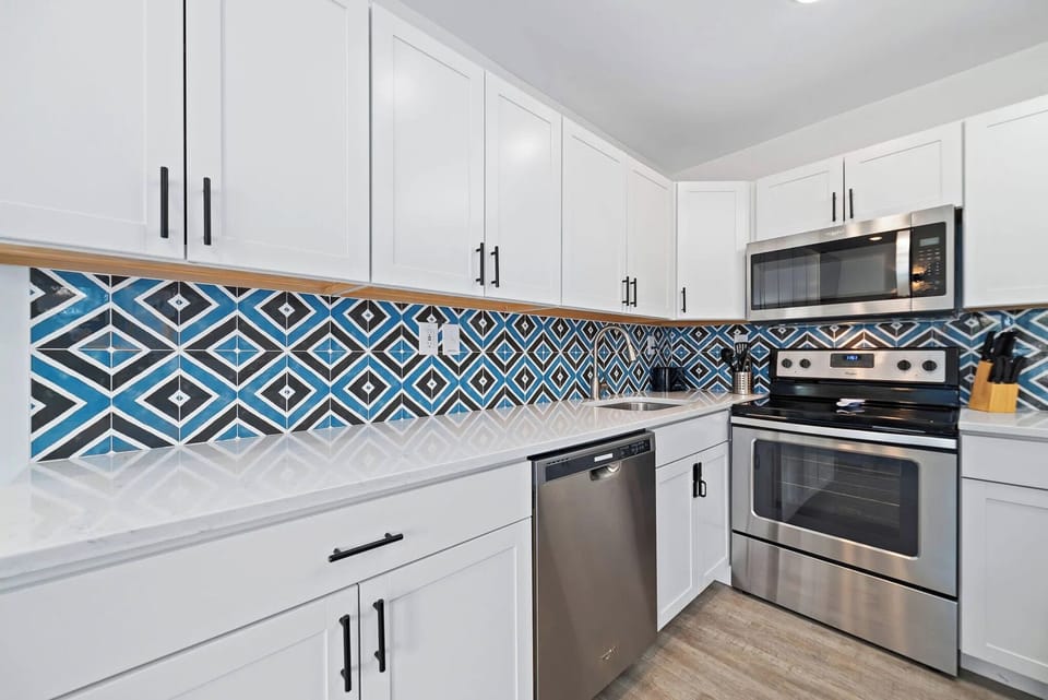 Bright and modern kitchen featuring sleek stainless appliances and a vibrant blue patterned backsplash
