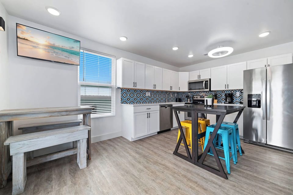 Kitchen featuring stainless appliances, colorful bar stools, and a view of the outdoors through the window