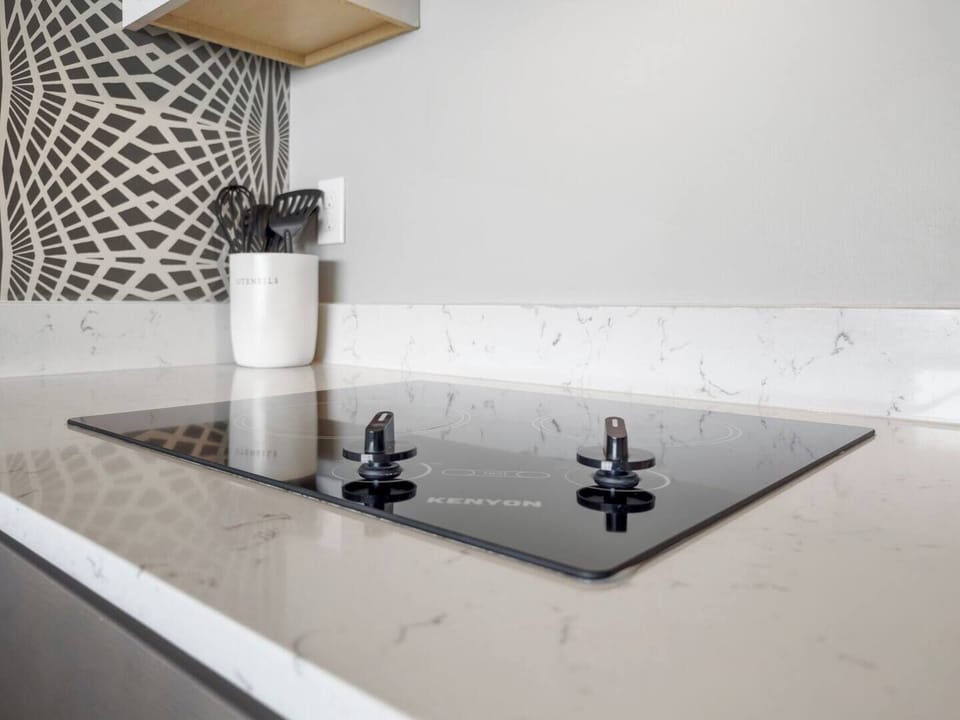 Sleek glass cooktop on marble countertop with modern controls & utensils