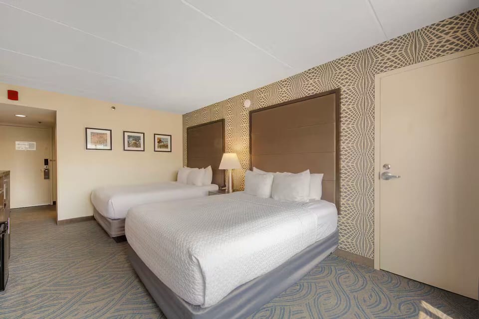 Inviting double queen room with plush beds, warm lighting & stylish accent walls