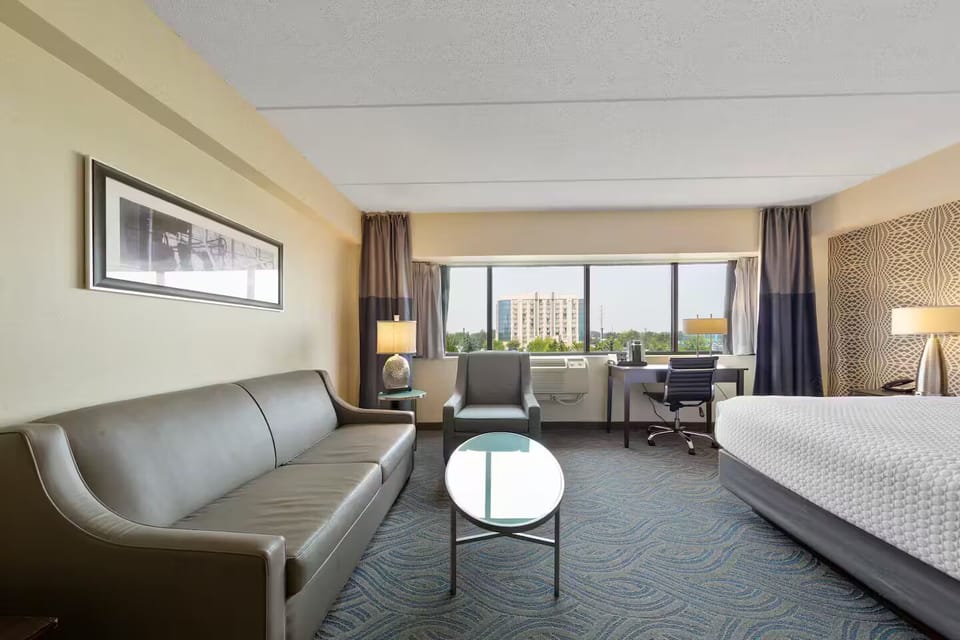 Spacious sitting area with leather sofa, armchair & coffee table with city views