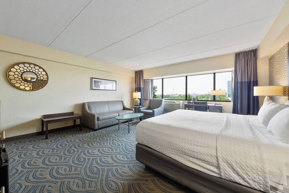 Bright room with king bed, leather sofa, desk & large windows with natural light