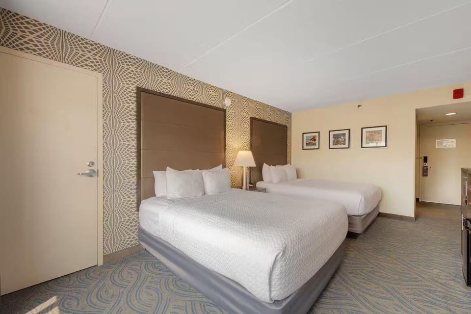 Inviting double queen room with plush beds, warm lighting & stylish accent walls