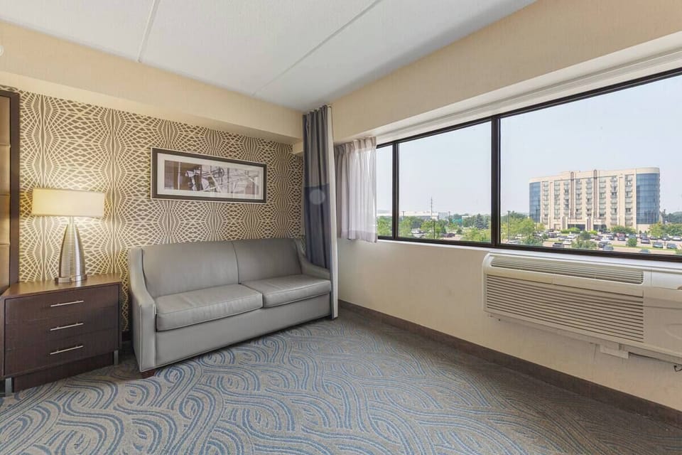 Cozy sitting area with leather loveseat, large window, modern lamp & wall art