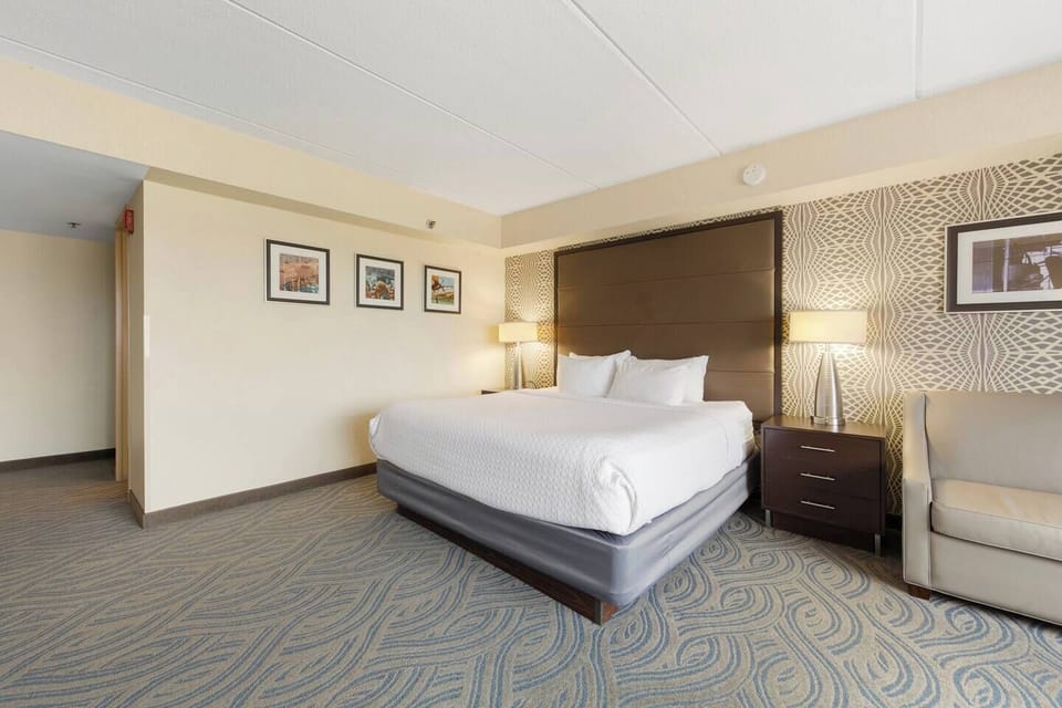 Inviting king bed with plush bedding, modern lamps & stylish accent wallpaper