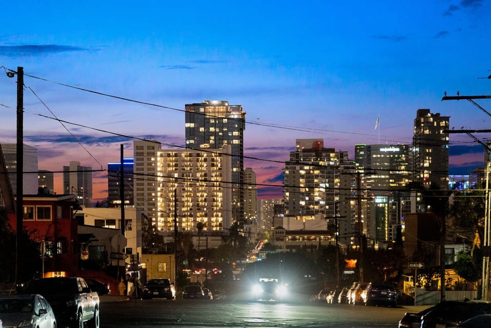 Glowing high-rises and a colorful sunset creating a lively urban scene.