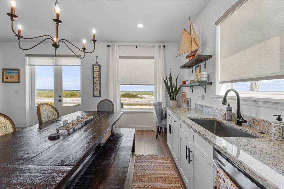 Modern kitchen and dining area with granite countertops and a view of the ocean.