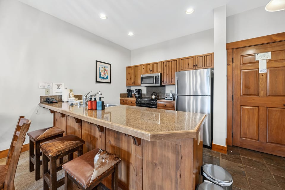 Kitchen breakfast bar with cowhide stools and granite.