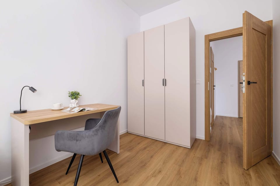 A closer look at a small workspace in the bedroom, featuring a wooden desk, a chair, and decorative elements on the desk, like a small plant.