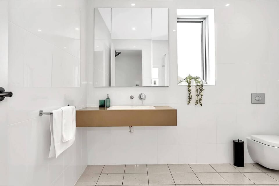The main bathroom features a walk-in shower, floating vanity, and modern finishes that complement the home’s coastal setting.