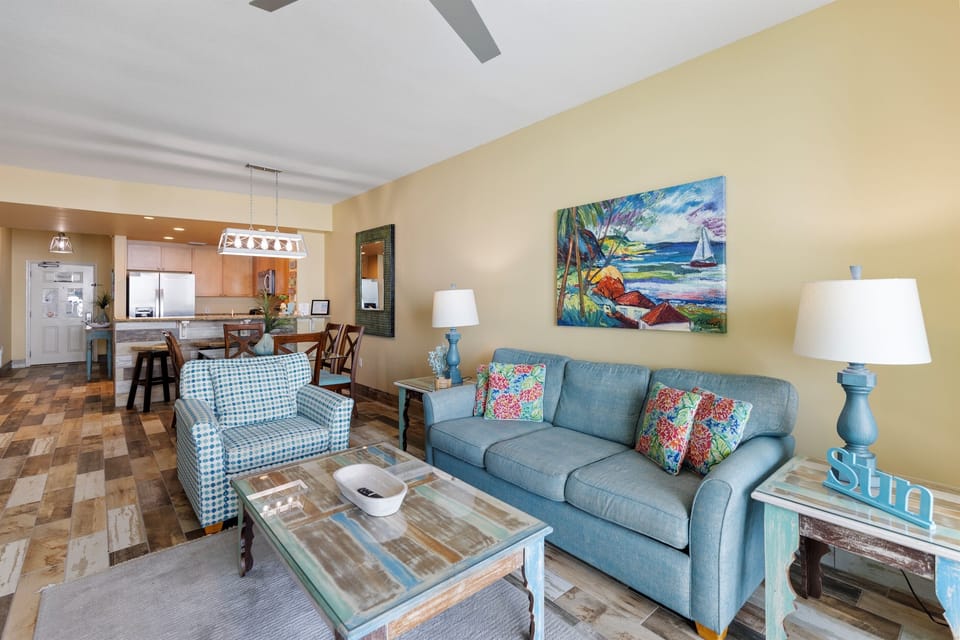 Unwind in your bright, open living space with coastal artwork and comfortable seating that flows seamlessly into the kitchen.