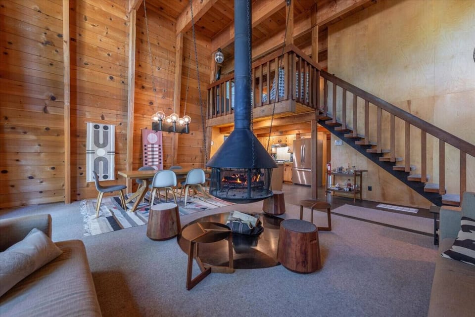 Open living room with comfy furnishings, dining area, and a floating wood burning fireplace!