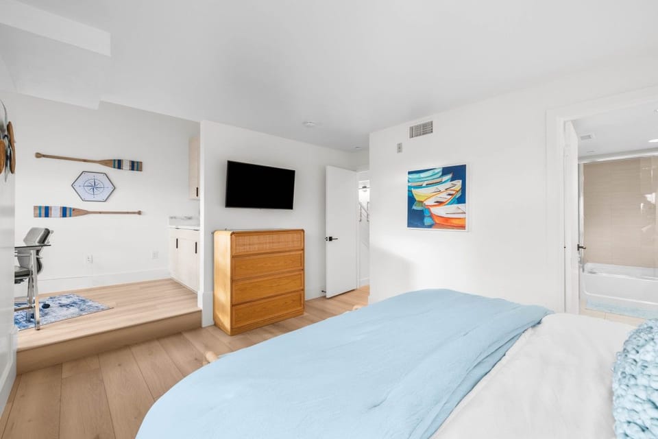 The primary suite includes a TV, dresser, and a raised workspace nook