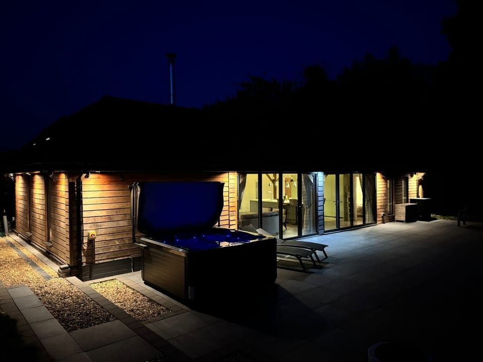 Spacious patio area featuring a luxurious hot tub perfect for relaxing while taking in the scenic views. Stunning bi fold doors in the kitchen open out to reveal expansive, fully fenced garden with views overlooking the cricket field. 