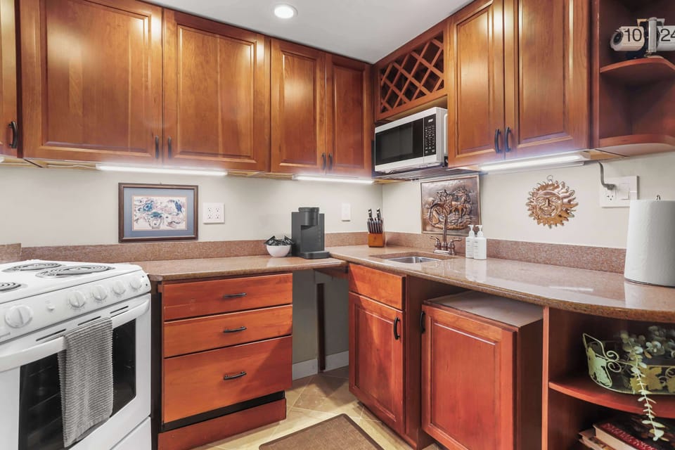 Fully equipped kitchen with spacious counter top, wooden cabinets and drawers.