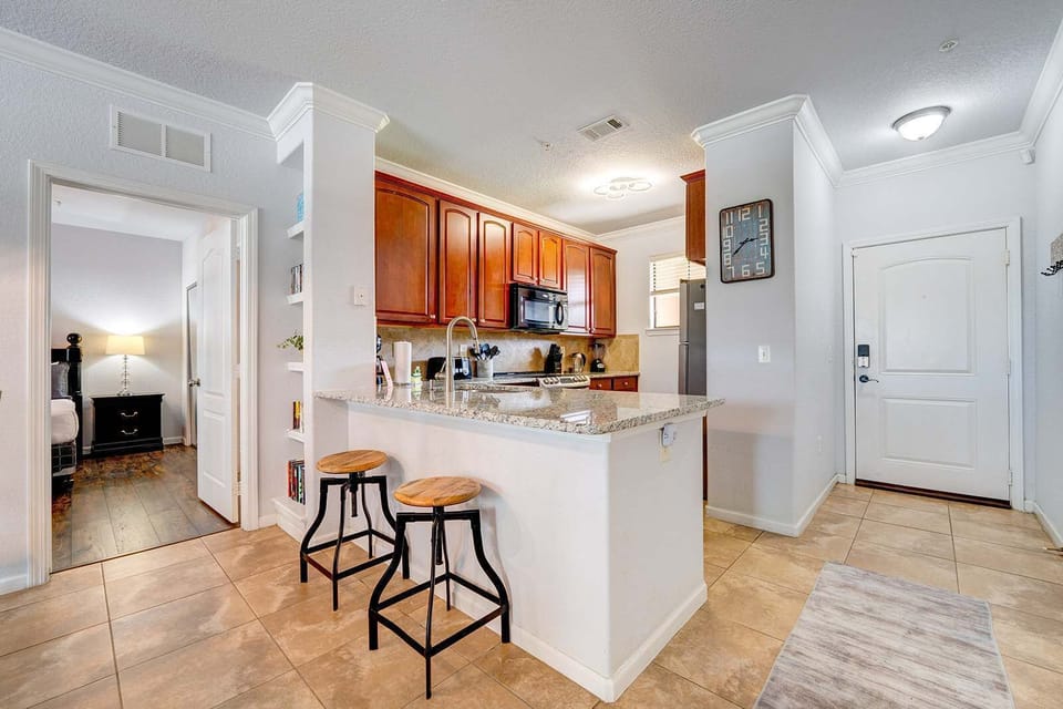 Modern kitchen with granite countertops and wooden cabinetry adjacent to the bedroom entrance