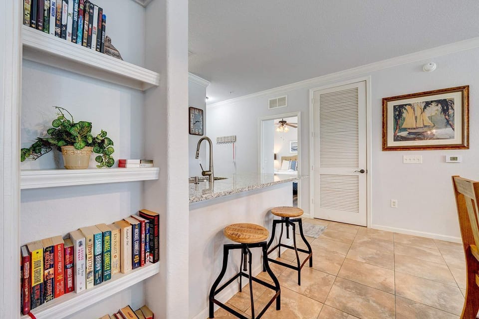 Cozy kitchen bar area with rustic stools and built-in bookshelves for a relaxing stay.