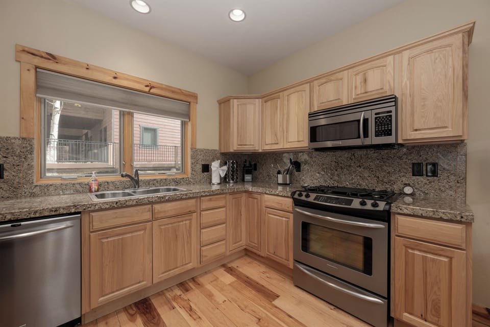 Cook comfortably in your fully equipped kitchen featuring granite counters, stainless appliances, and warm wood cabinetry.