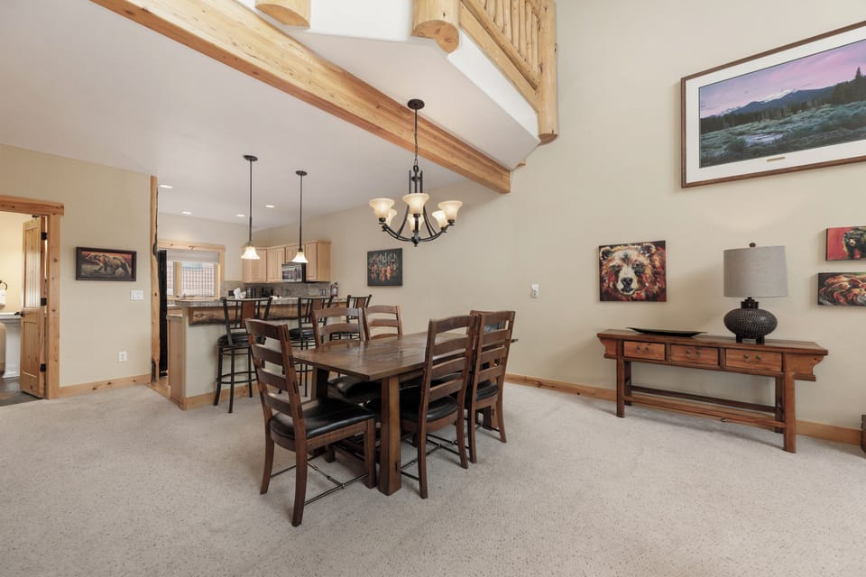 Gather around your spacious dining table beneath soaring wood beams, where warm mountain lodge charm meets modern comfort for memorable meals together.