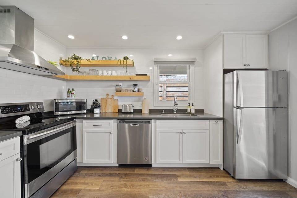 Fully equipped kitchen with stainless steel appliances and floating shelves for a modern touch.