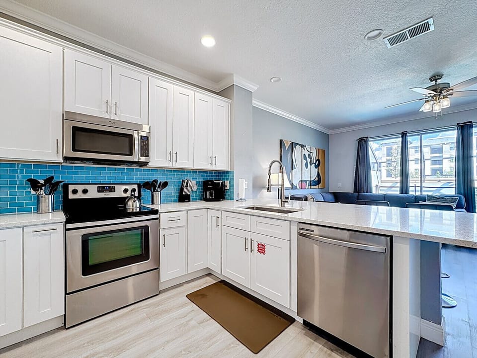 Fully equipped kitchen with stainless steel appliances and vibrant backsplash.
