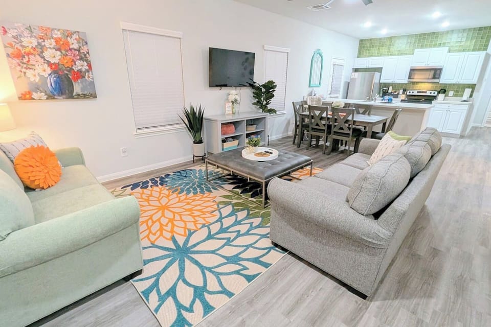 Cozy living room with two couches, ottoman, and open concept access to the dining area. Relax while watching the Roku smart TV or play some board games with the family. 