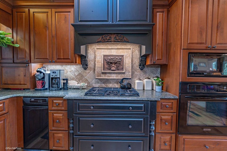 Gourmet kitchen with gas range, rich wood finishes, and all the cookware you need for home-style meals.