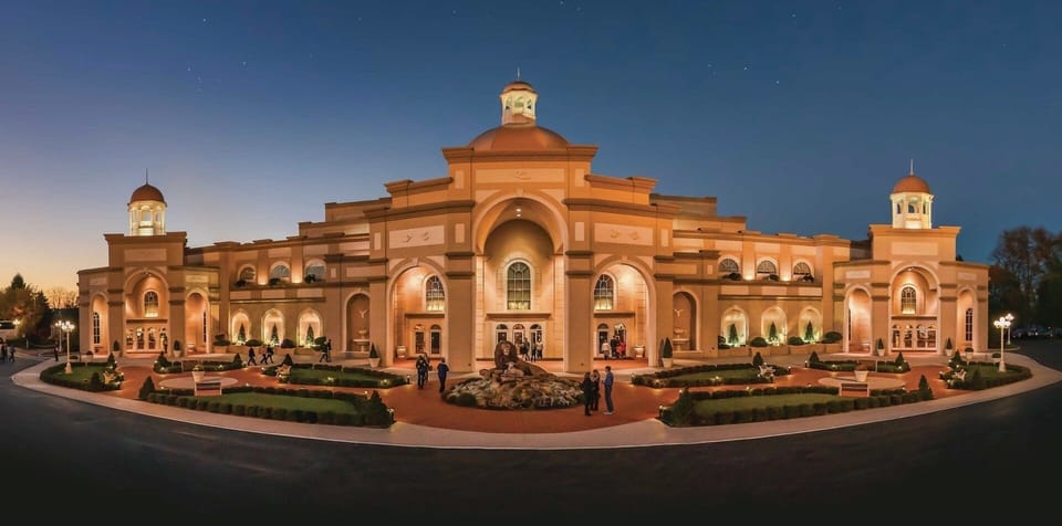 Arrive to a grand, warmly lit entrance at dusk.