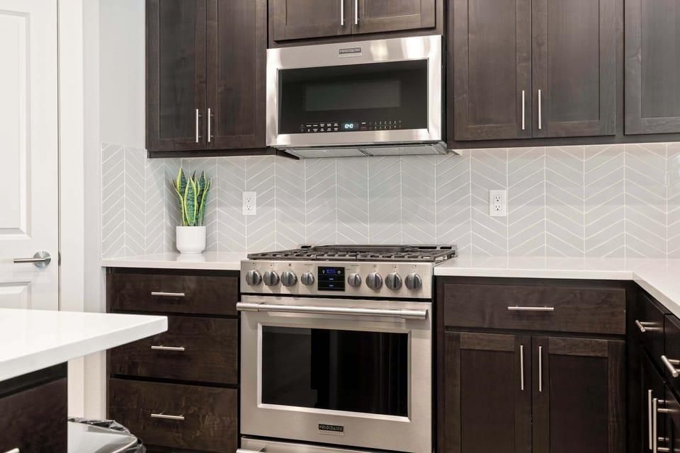 Sleek oven and microwave framed by modern dark cabinets and a clean tile backsplash.