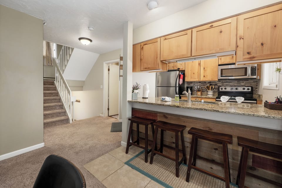 Well-stocked kitchen with stainless steel appliances and breakfast bar seating