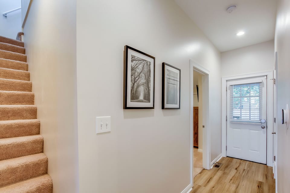 Hallway leading to 2 upstairs bedrooms and downstairs primary suite + backyard