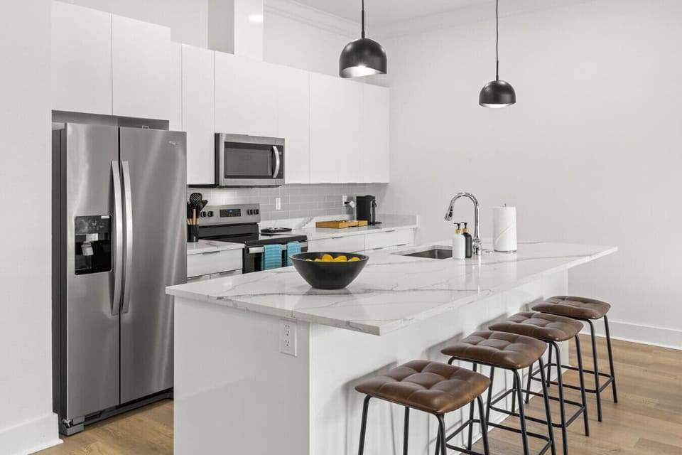 Updated kitchen offers white granite countertops, stainless steel appliances, Nespresso machine and bar seating