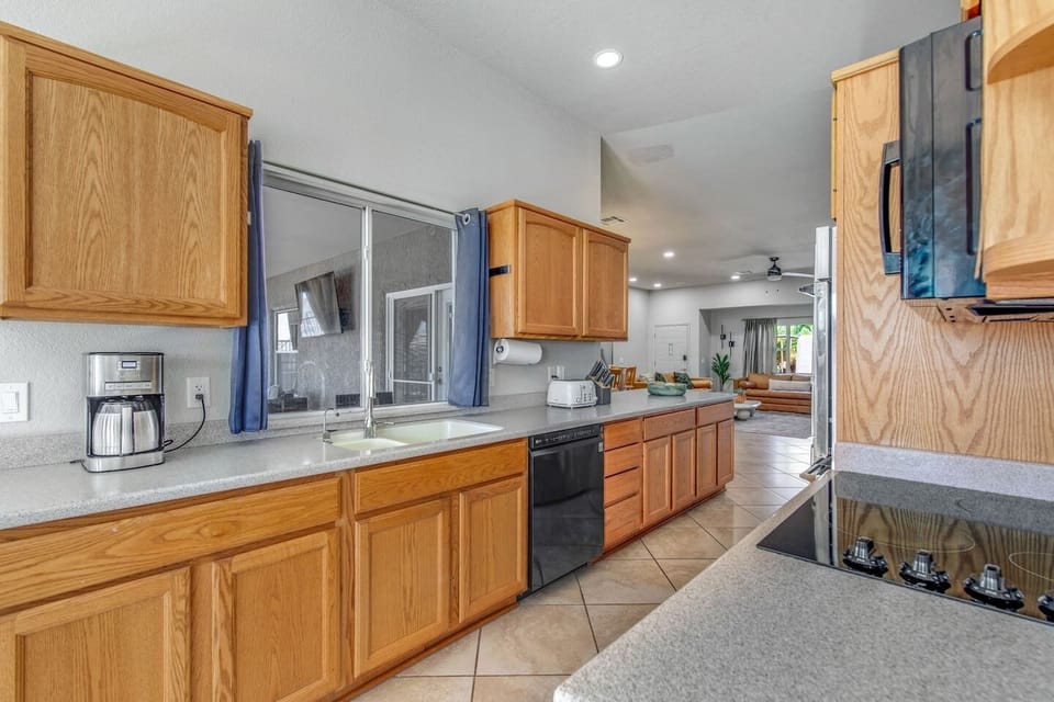 Modern kitchen with supplies, air fryer, blender, drip coffee maker, and electric stovetop.  Fully stocked kitchen ready for cooking, with coffee, blender, air fryer, and stovetop.