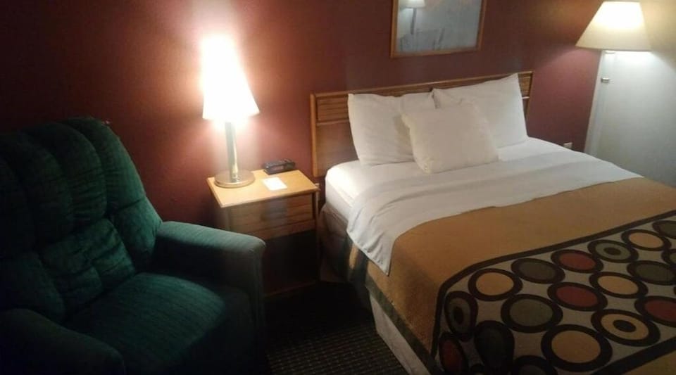 Relax into a cozy armchair beside your freshly made bed.