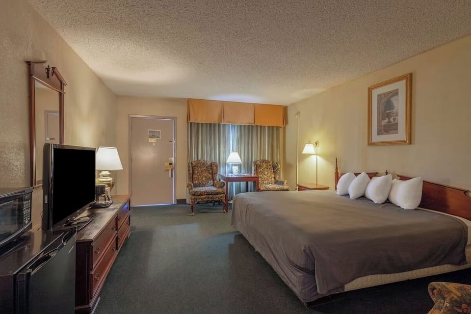 Unwind in a spacious room with bed, TV, and lounge chairs.