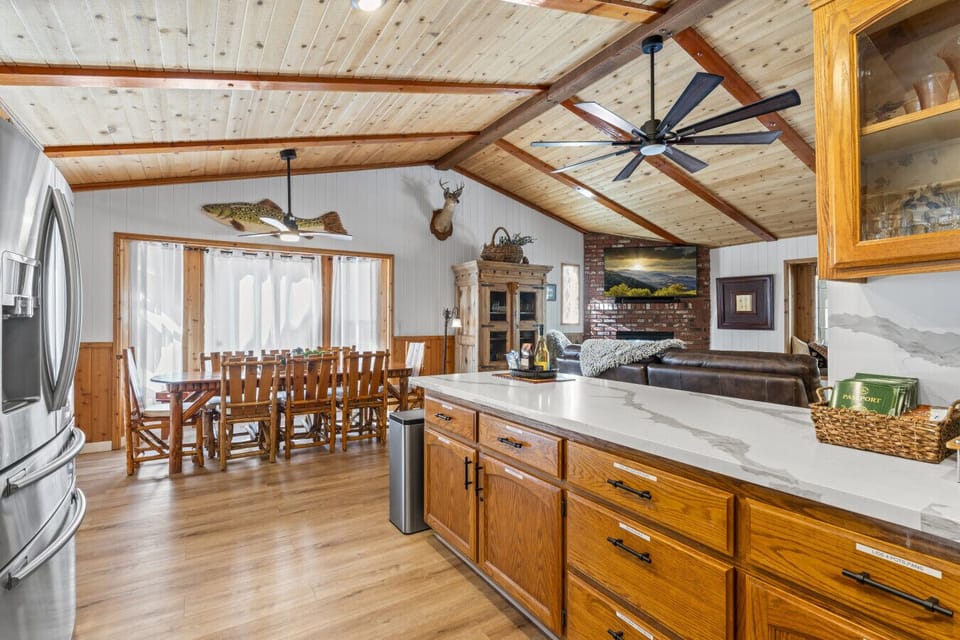 Spacious kitchen w/ long breakfast bar, wood cabinetry & open flow to dining area.